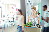 Woman carrying cardboard box in office