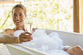 Woman having champagne in bubble bath