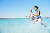 Couple running in water on beach