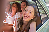 Four women playing in car backseat