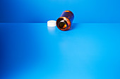 Empty pill bottle open on blue counter