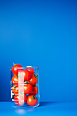 Beaker of small tomatoes on blue counter