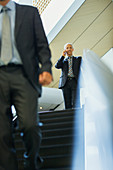 Businessman talking at top of escalator