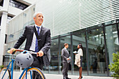 Businessman walking bicycle