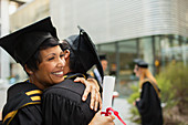 Students in cap and gown hugging