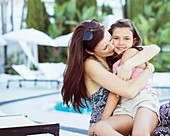 Mother embracing her daughter on poolside