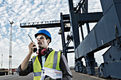 Worker using walkie-talkie near crane