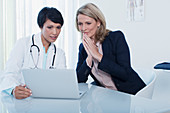 Female doctor and patient using laptop