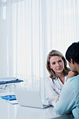 Female doctor talking to woman at desk