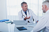 Mature doctor talking to patient at desk