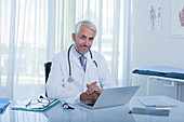 Mature doctor at desk with laptop