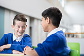 Schoolboys talking at desk