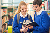 Students looking at book in library