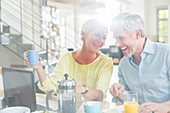 Older couple laughing at breakfast table