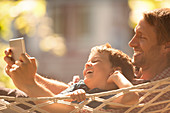 Father and son using tablet in hammock