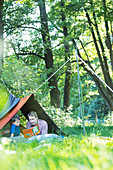 Father and son reading in camping tent