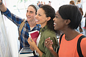 Three smiling students looking at board