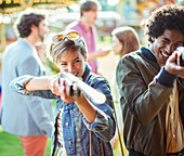 Young couple aiming with guns