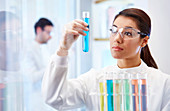 Woman looking at vial with blue fluid