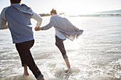 Young couple holding hands and running