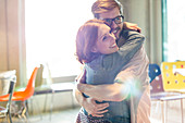 Smiling couple hugging in sunny room