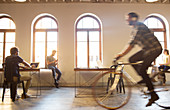 Businessman riding bicycle in open office