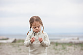 Curious girl examining pebbles on beach