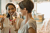 Smiling women wine tasting white wine in winery tasting room