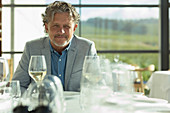 Portrait confident man with white wine at sunny restaurant t