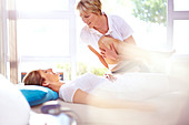 Physical therapist stretching woman's leg