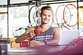 Smiling man drinking coffee in bike shop
