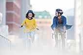 Young couple riding bicycles in city