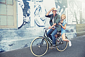 Portrait playful couple riding bicycle