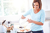 Woman cooking tomato quiche in kitchen