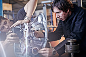 Mechanics fixing part in auto repair shop