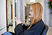 Woman texting in hair salon
