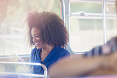 Smiling woman with afro texting on bus
