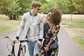 Couple walking with bicycle in park