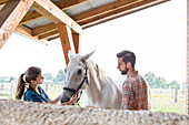 Couple petting horse in rural stable