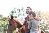 Smiling couple hugging near horse