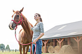 Woman with horse outside rural barn