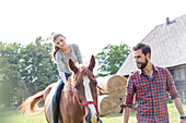 Man leading woman horseback riding