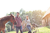 Couple walking horse outside rural barn