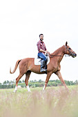 Man horseback riding in rural field