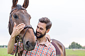 Smiling man hugging horse