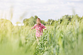 Carefree boy running in sunny rural field