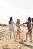 Boho women holding hands and dancing