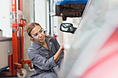 Female mechanic examining car