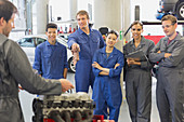Mechanic students discussing car engine