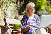 Senior woman using laptop in garden